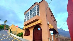 A building with a two-story structure, a red door, and a small staircase leading to the entrance. - Guest House las 7 islas, Green Room (Adeje)
