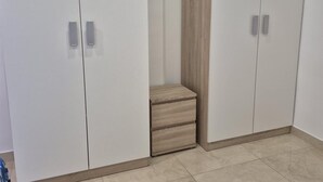 A room with white wardrobes, a wooden bench, and tiled flooring. - Guest House Las 7 Islas, White Room Airco (Adeje)