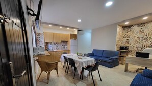 A compact living space with a dining area, kitchenette, and a sofa. - Guest House Las 7 Islas, White Room Airco (Adeje)
