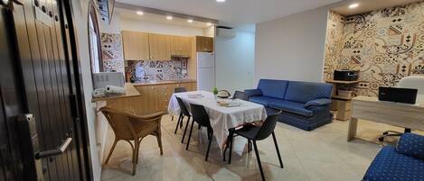 A compact living space with a dining area, kitchenette, and a sofa.