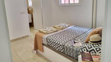 Een slaapkamer met een bed, een raam, een televisie en een deur naar een badkamer.