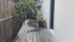 Une terrasse en bois avec une chaise en métal et des plantes en pot.