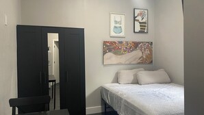 Une chambre à coucher avec un lit, un bureau, une chaise et une porte.