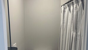 Une petite salle de bain compacte, équipée de toilettes, d’un rideau de douche et d’un lavabo encastré.