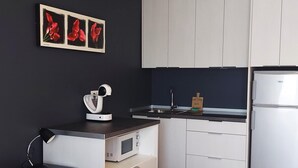 A compact kitchen with a microwave, kettle, and a refrigerator. There is a sink with a faucet and a small wooden sign on the counter. - Mareverde Resort, Blue Studio (Costa Adeje)