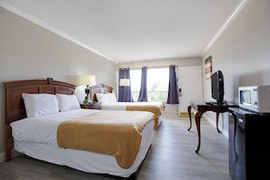 A hotel room with two beds, a television, a desk with a computer, and a window with curtains. - Riverside Inn and Suites Danville Virginia (Danville)
