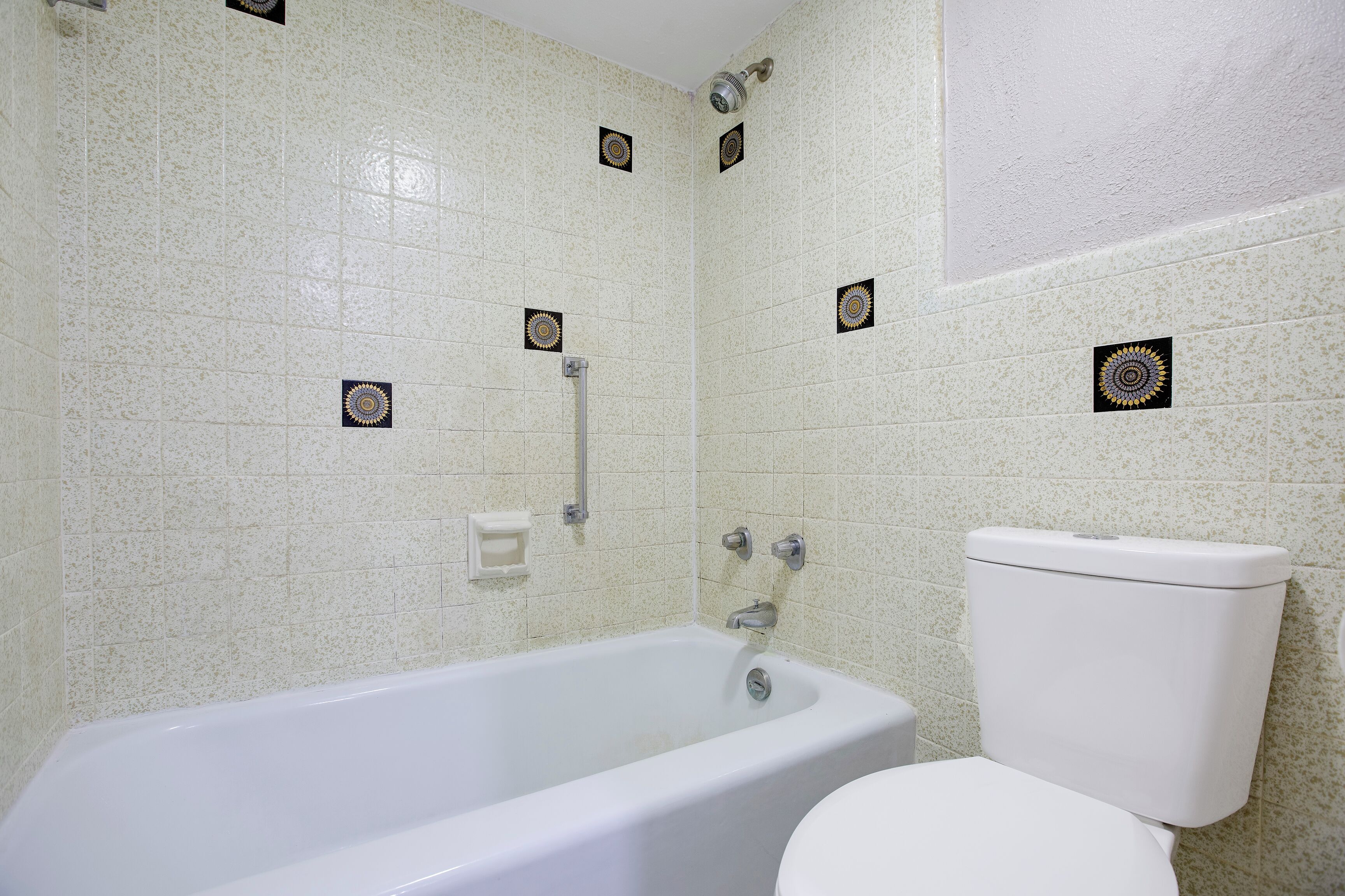 A bathroom with a bathtub, toilet, and a showerhead.