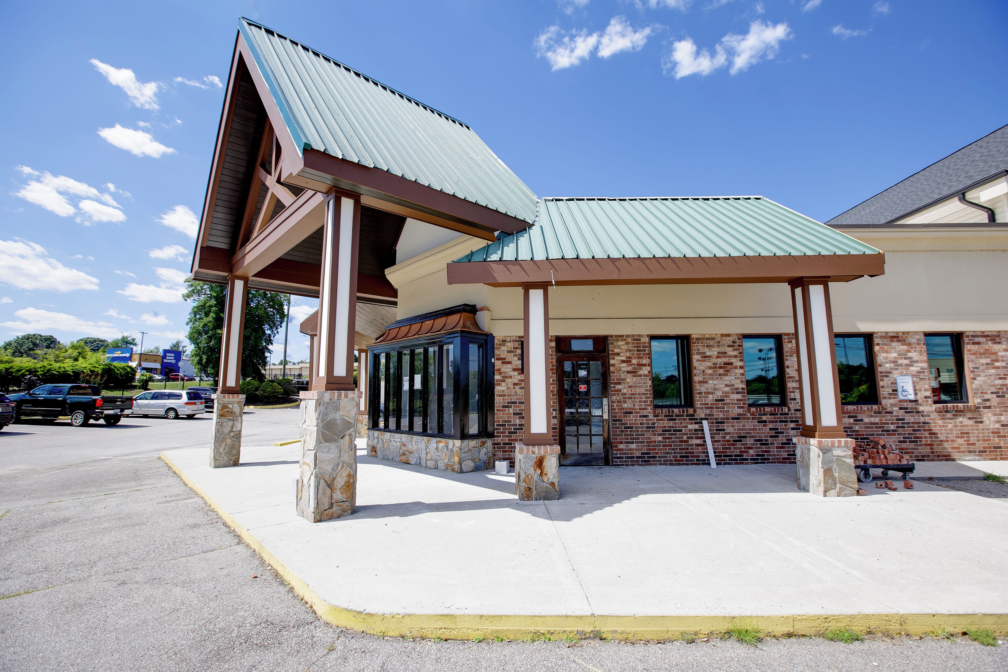 A building with a covered entrance, stone pillars, and a brick facade.