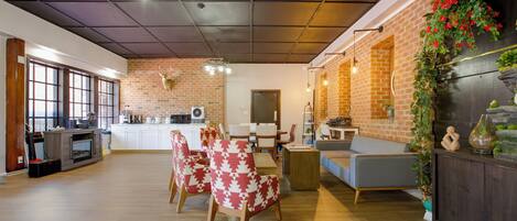 Amplia sala de estar con cocina, comedor y una zona de estar con sillas y sofá.