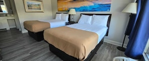 Quarto de hotel com duas camas, um quadro na parede e uma janela com cortinas.