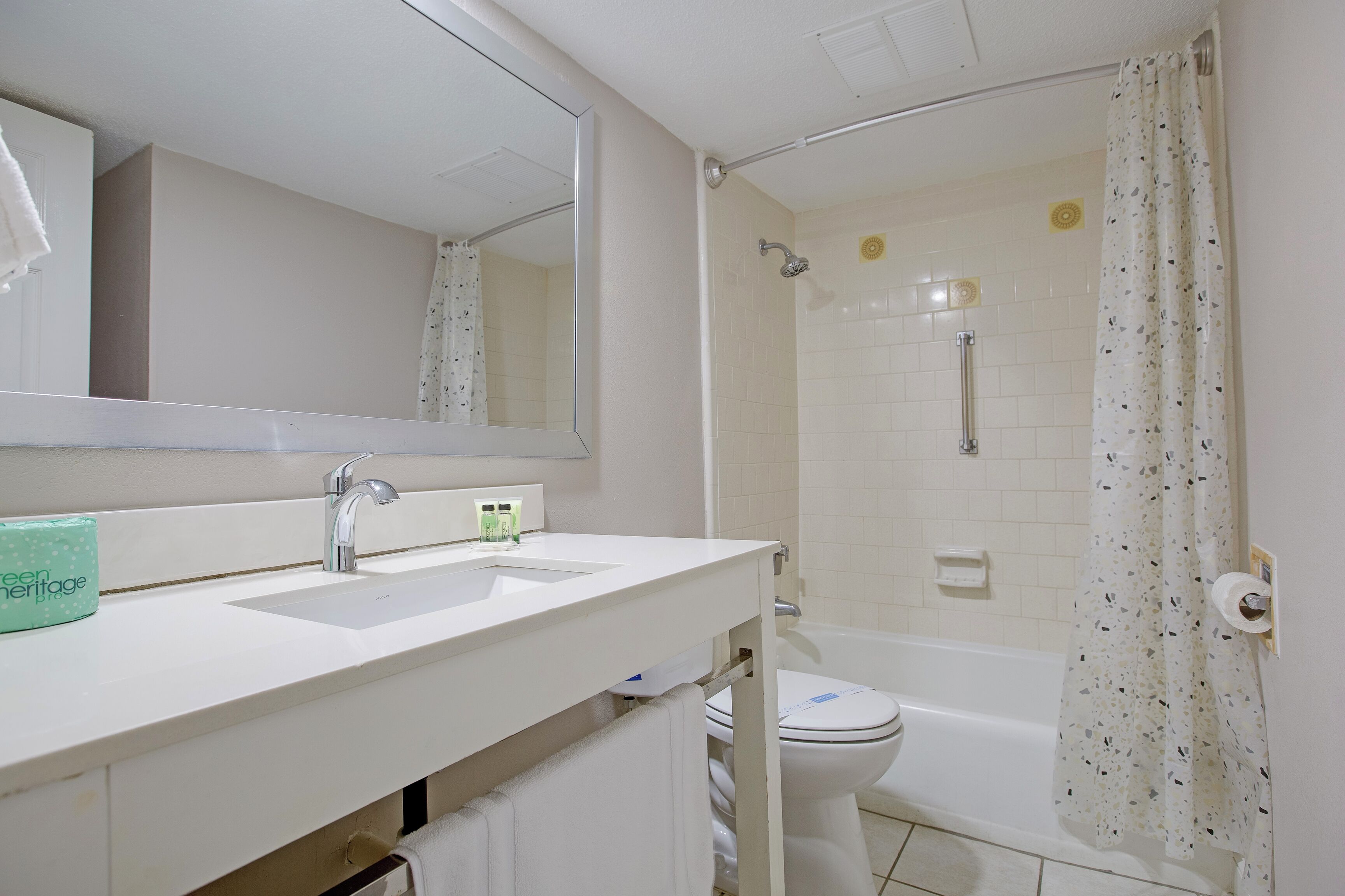A bathroom with a white sink, a mirror, a shower with a glass door, and a toilet.