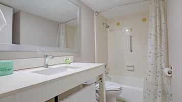 A bathroom with a white sink, a mirror, a shower with a glass door, and a toilet.