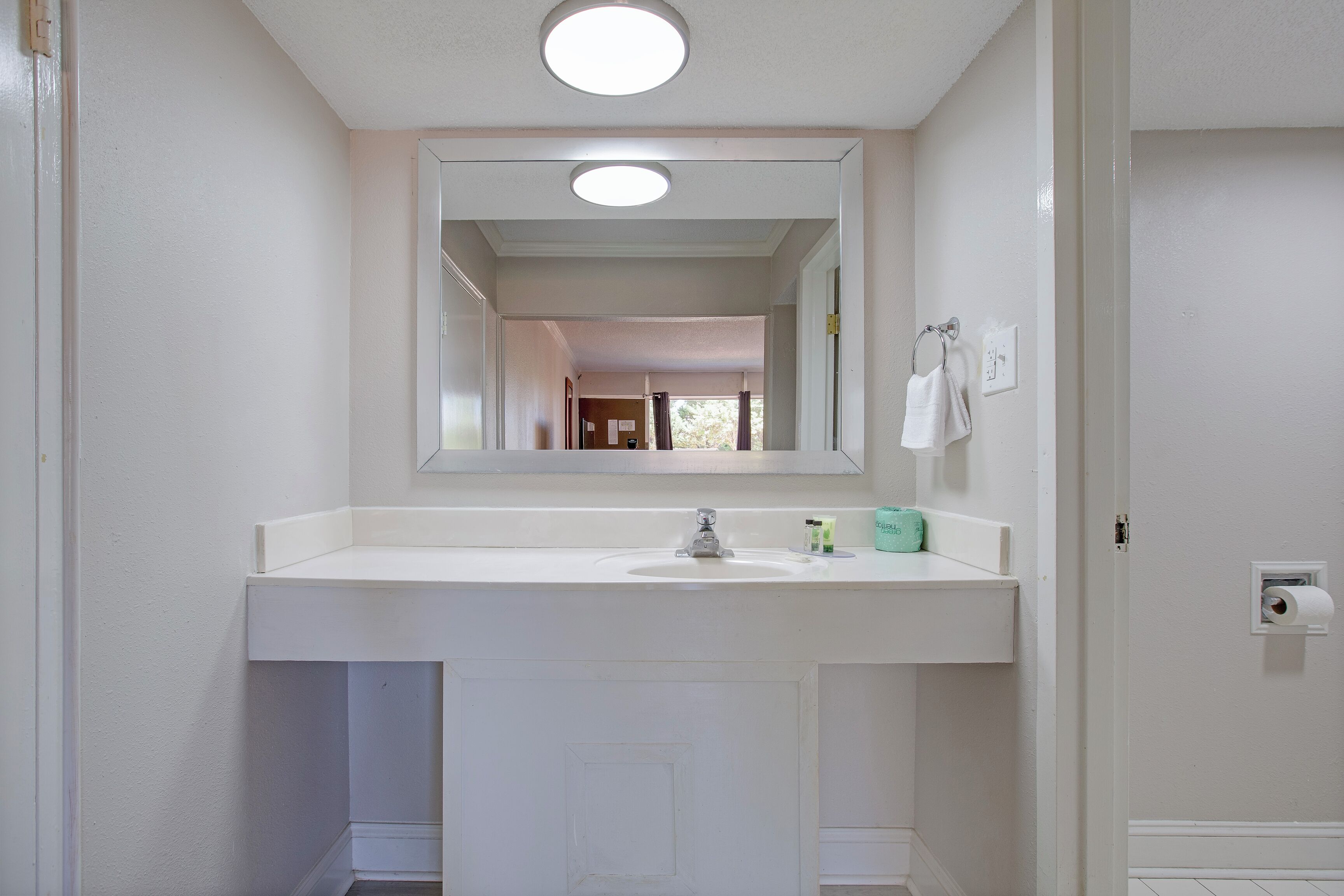 A bathroom with a white sink, a mirror above it, and a towel hanging on a rack.