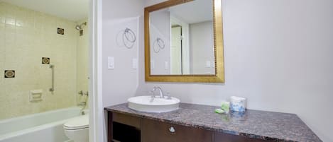 Un baño con un lavabo blanco, un espejo grande con marco dorado, una ducha y un inodoro.