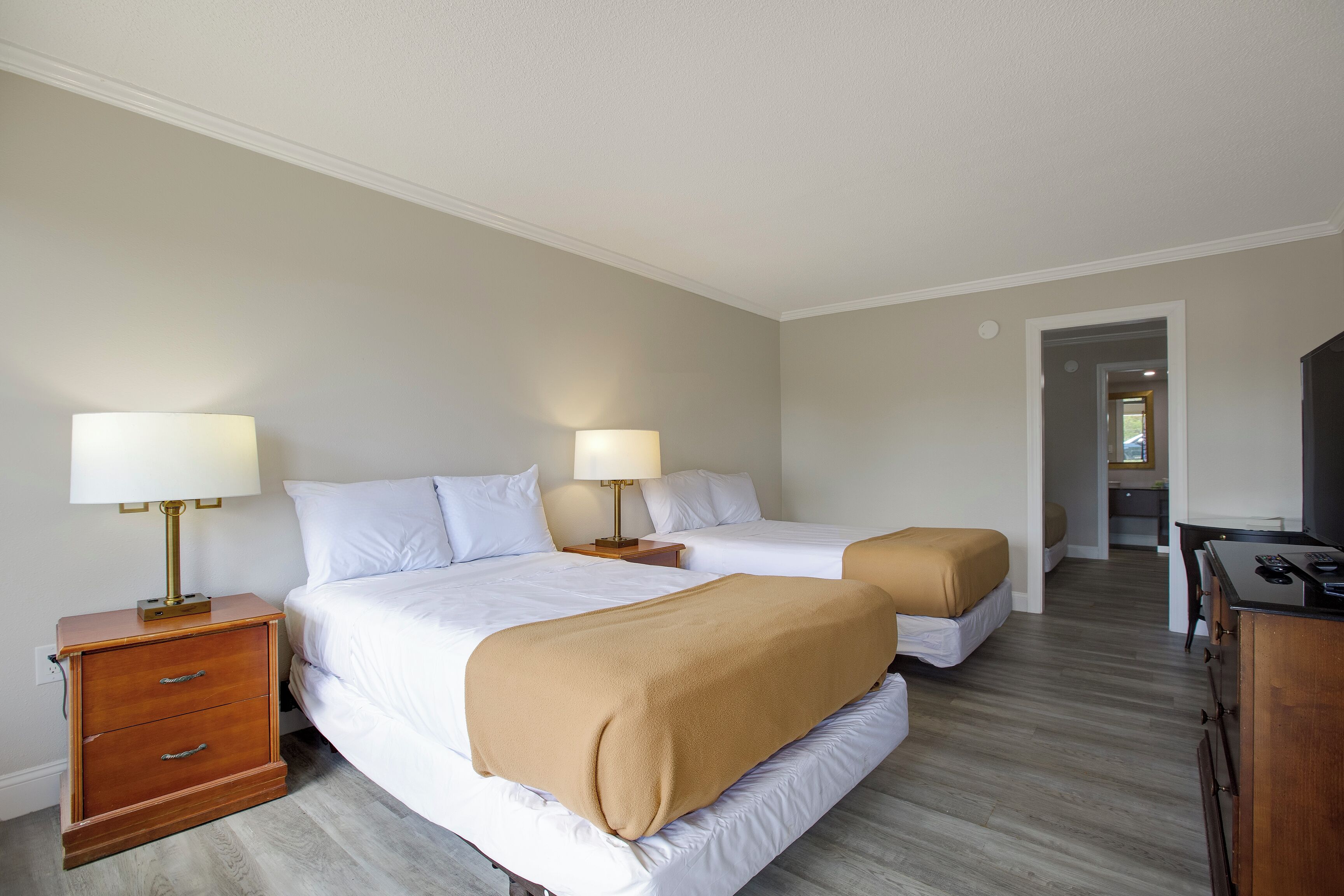 A hotel room with two beds, a desk, and a chair.