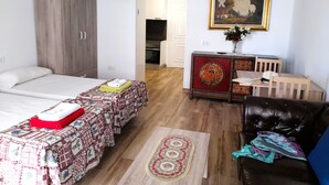 Une chambre avec deux lits, un bureau, une chaise, une télévision et un tableau au mur.