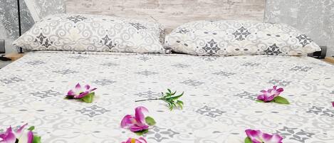 A bed with patterned bedding, pillows, and decorative flowers.