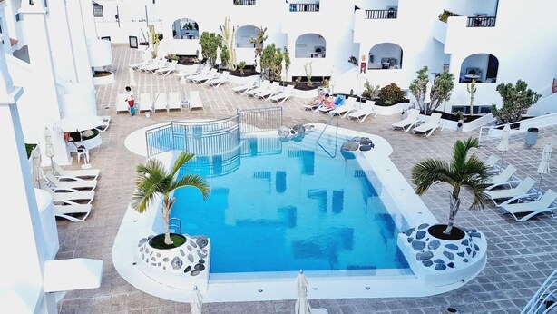 A rooftop pool area with lounge chairs and palm trees. - Garajonay 3 bedrooms apartment, ocean pool view (Costa de Adeje)