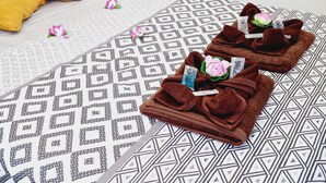 A neatly made bed with patterned bedding, two brown towels with flowers, and a yellow pillow. - Garajonay 3 bedrooms apartment, ocean pool view (Costa de Adeje)