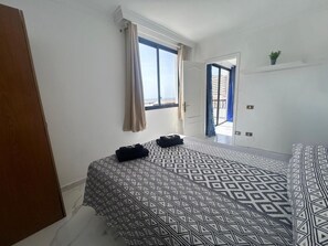Een slaapkamer met een bed, een deur en een raam.