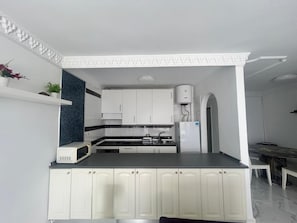 Cozinha moderna com armários brancos, bancada preta e micro-ondas embutido.