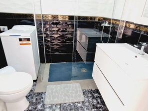 Une salle de bain comprenant des toilettes, un lavabo et un espace douche.