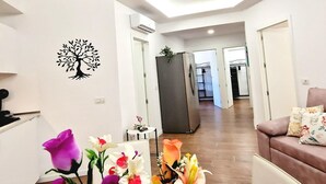 Un salon moderne avec un canapé, un motif décoratif représentant un arbre appliqué sur le mur et un arrangement floral.