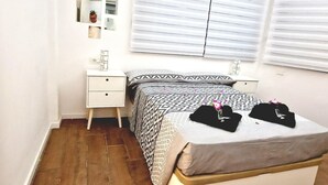 Une chambre à coucher avec un lit, une table de chevet, un miroir et une fenêtre avec des stores.