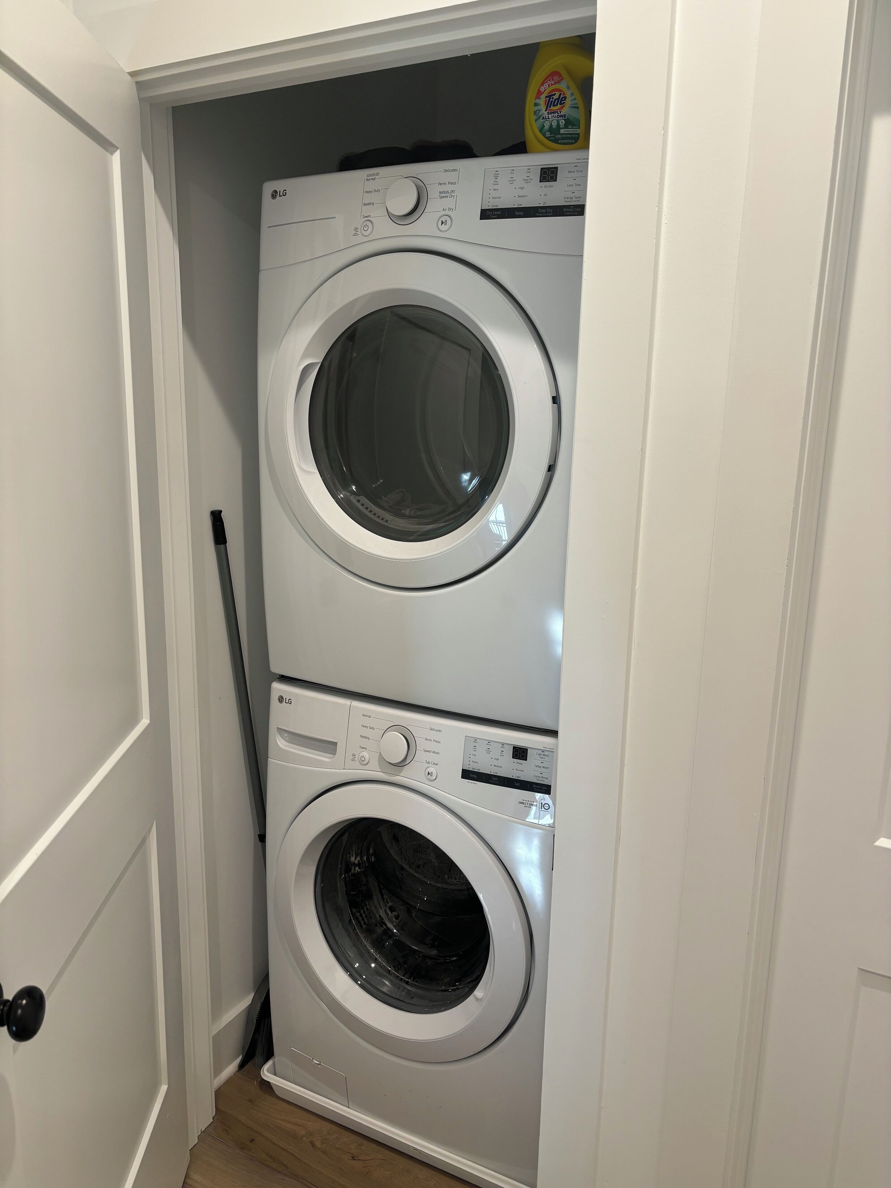 A compact, two-door laundry room with a white door and a wooden floor.