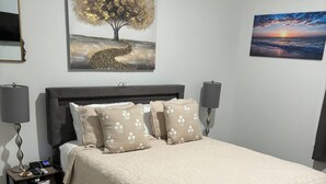 A bedroom with a bed, two bedside tables, a nightstand, a lamp, and two wall-mounted lamps.