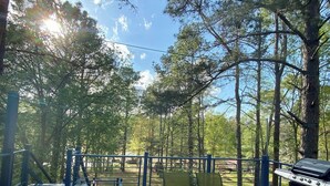 Une terrasse extérieure avec une table et des chaises, entourée d’arbres.