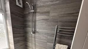 A modern bathroom with a freestanding bathtub, a shower with a handheld showerhead, and a towel rack. - 6-bed 3-bath Home - Sleeps 14 & Free Parking (Uxbridge)