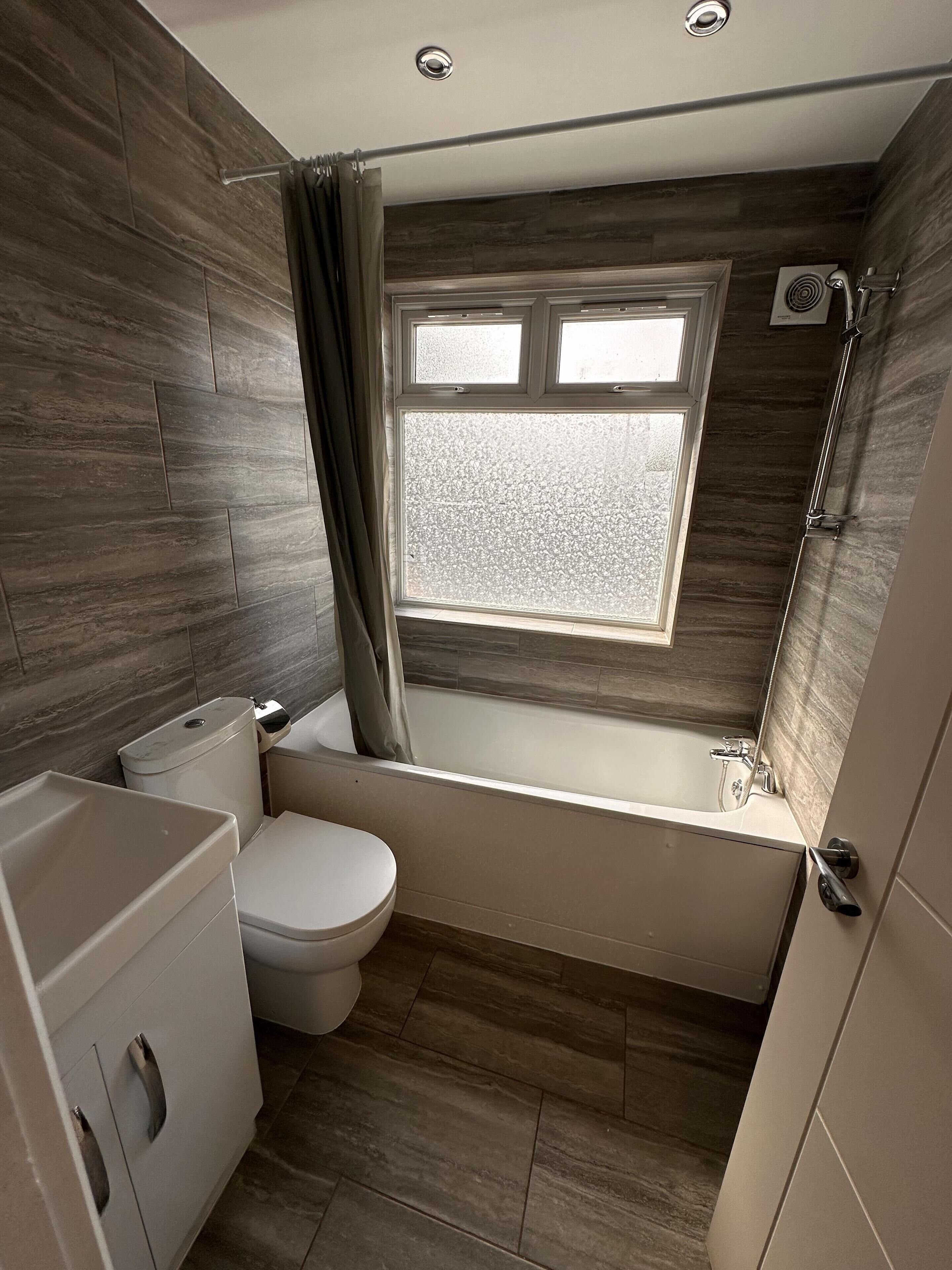 Un baño moderno con bañera, inodoro y ventana.