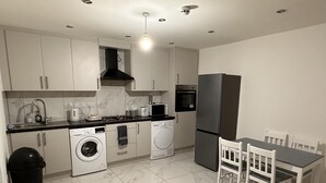 A compact kitchen with a washing machine, a refrigerator, a microwave, and a sink. - 6-bed 3-bath Home - Sleeps 14 & Free Parking (Uxbridge)
