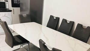 A modern kitchen with a marble countertop, black chairs, and stainless steel appliances. - 6-bed 3-bath Home - Sleeps 14 & Free Parking (Uxbridge)