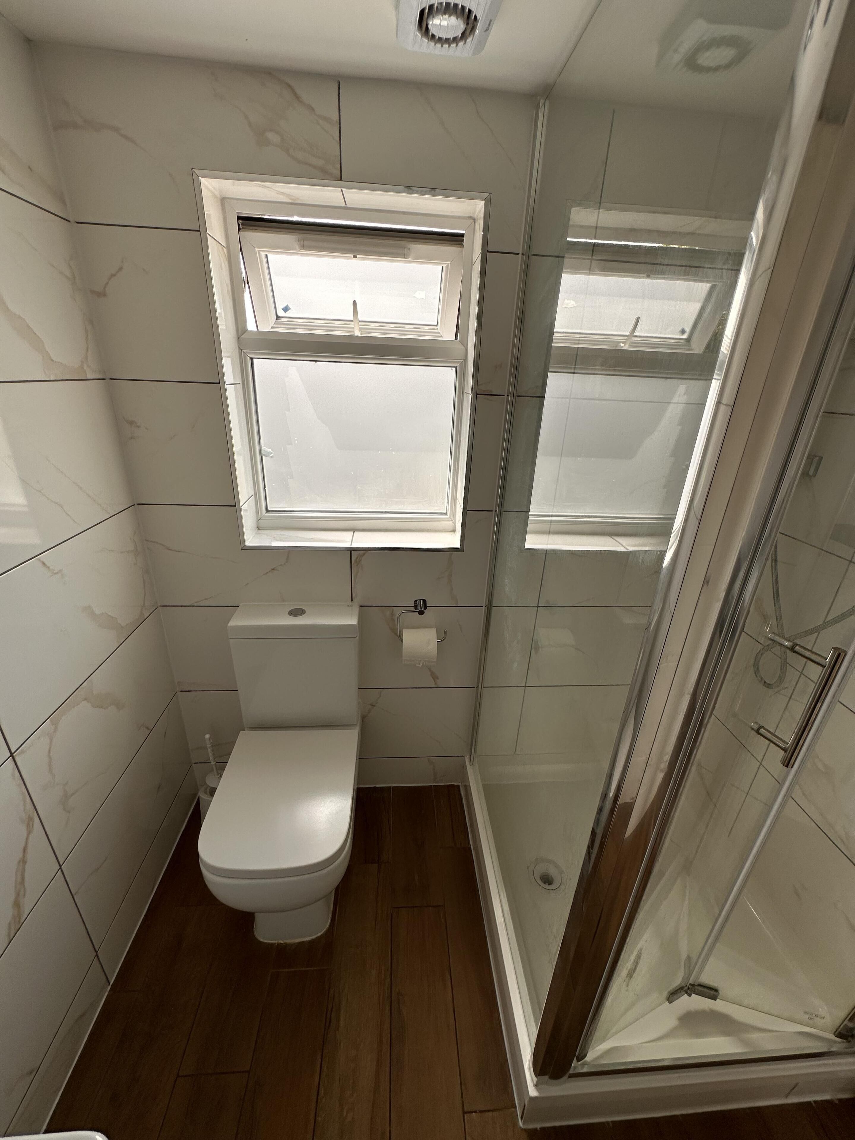 Ein Badezimmer mit Toilette, Dusche und Fenster.