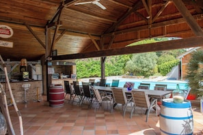An outdoor patio with wooden tables and chairs, a pool, and a café area.