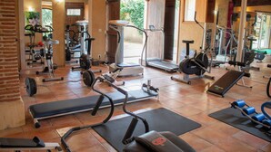 Een sportschool met trainingsapparatuur, een bank en een spiegel.