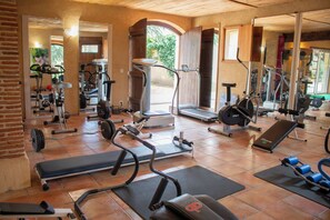 A gym with exercise equipment, a bench, and a mirror.