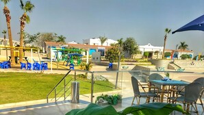 A patio area with outdoor seating, a children's play area, and a view of the surrounding buildings. - Grand Plaza Hotel (Kirdasah)
