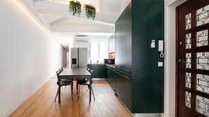 Een moderne keuken met donkergroene kastjes, een houten eettafel met stoelen en hangplanten.