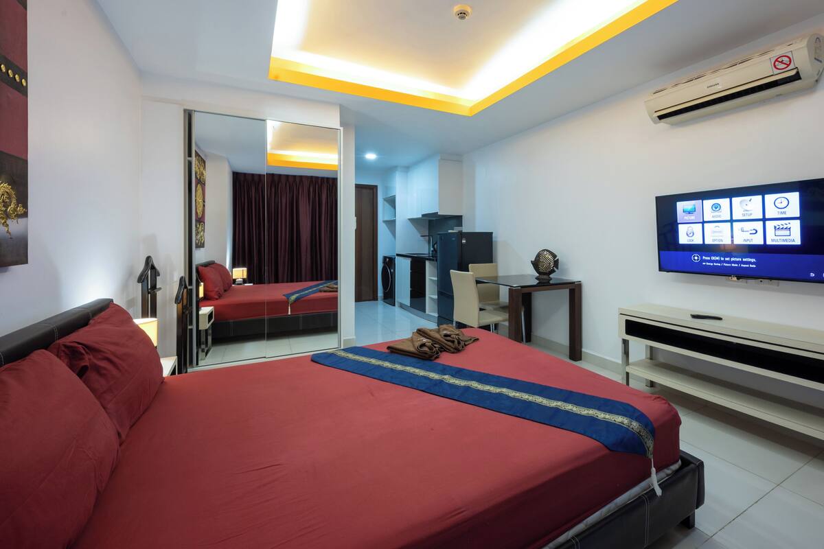 Een hotelkamer met een bed, een televisie, een bureau en een spiegel.