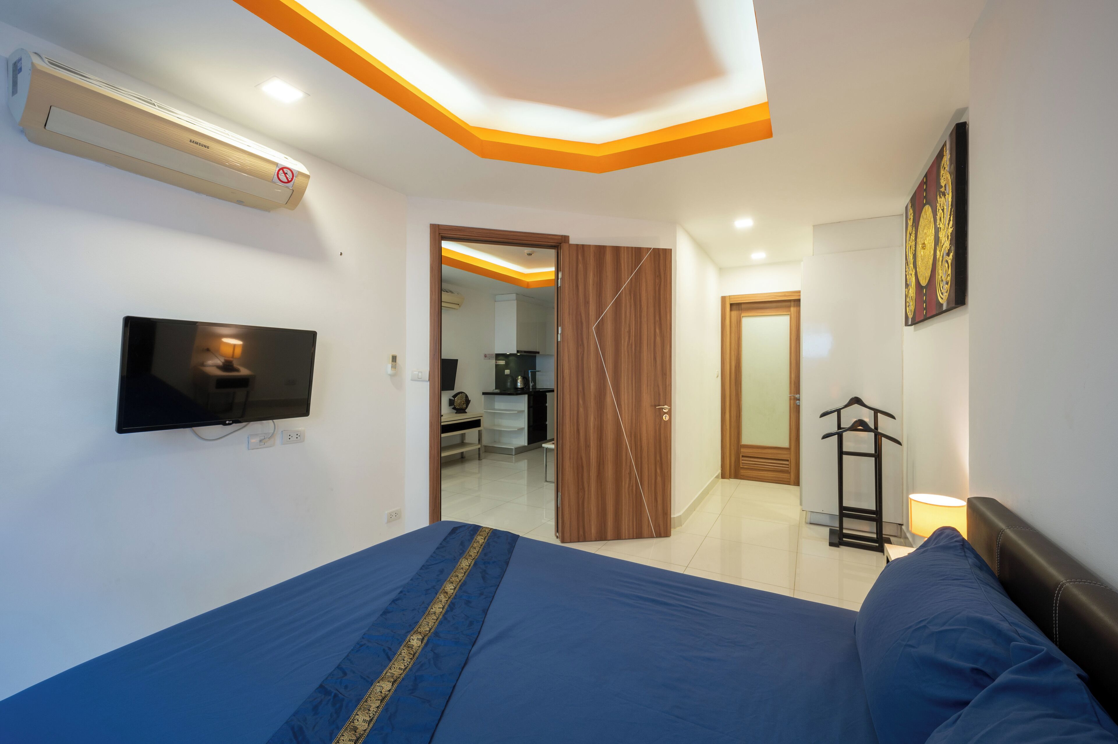 A bedroom with a bed, a TV, a wardrobe, and a mirror.