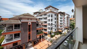 Un edificio residencial de varios pisos con balcones, un garaje y una vista despejada de la calle.