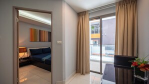 Habitación de hotel con cama, escritorio, lámpara, ventana con cortinas y vistas al exterior.