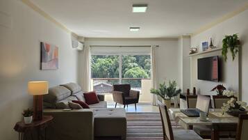 A modern living room with a sofa, armchair, and a dining area with a table and chairs.