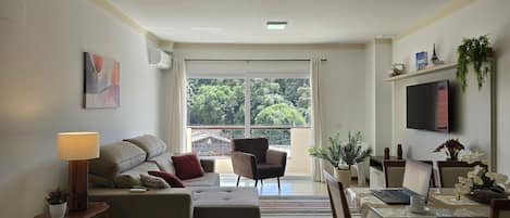 Una sala de estar moderna con un sofá, un sillón y un comedor con una mesa y sillas.