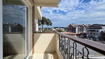Un balcón con vista a un pueblo, un árbol y edificios al fondo.