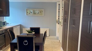 Una cocina moderna con armarios de madera oscura, una mesa de comedor con sillas y un piso de baldosas.