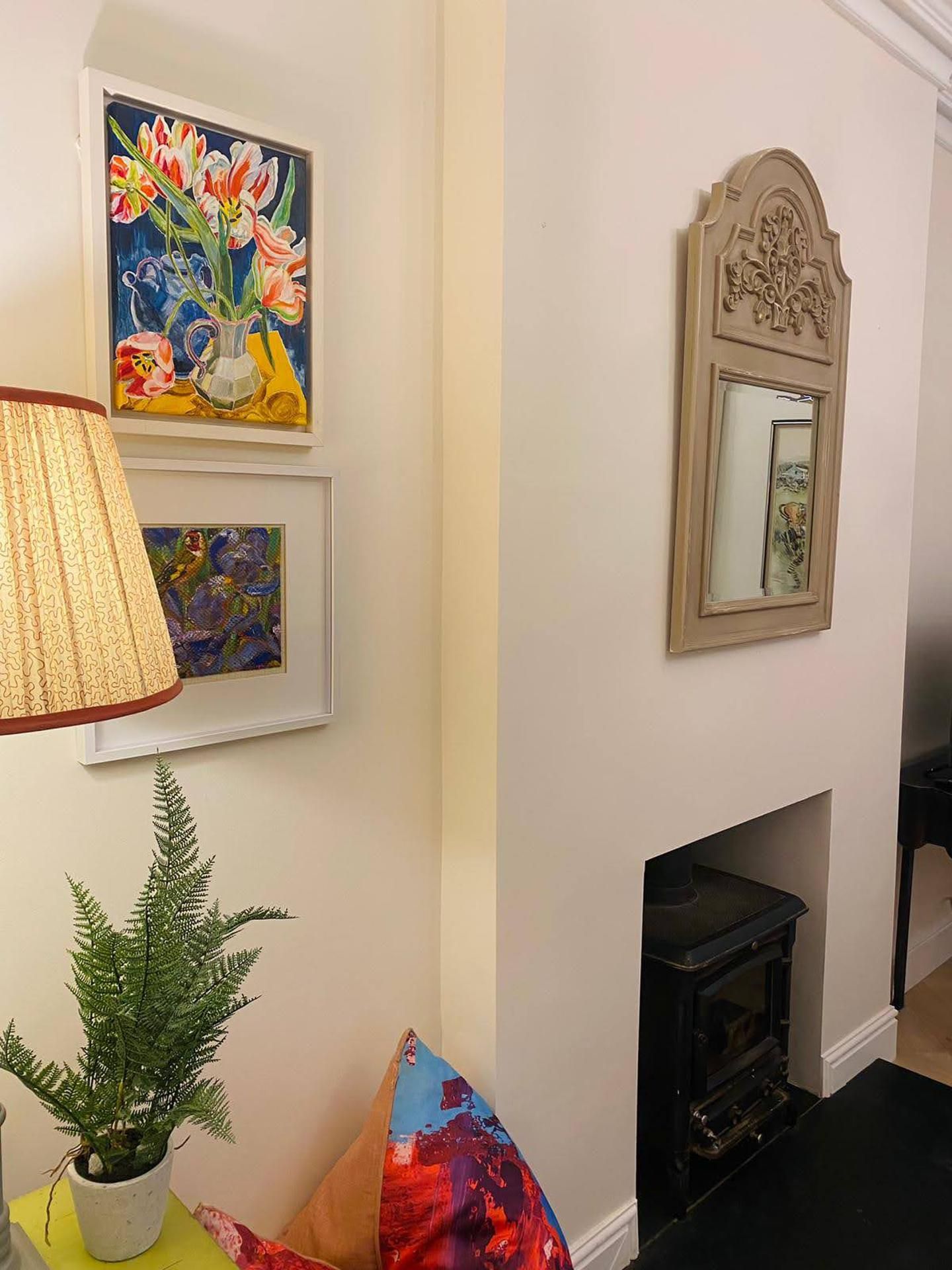 A room with a fireplace, a lamp, and two framed paintings.